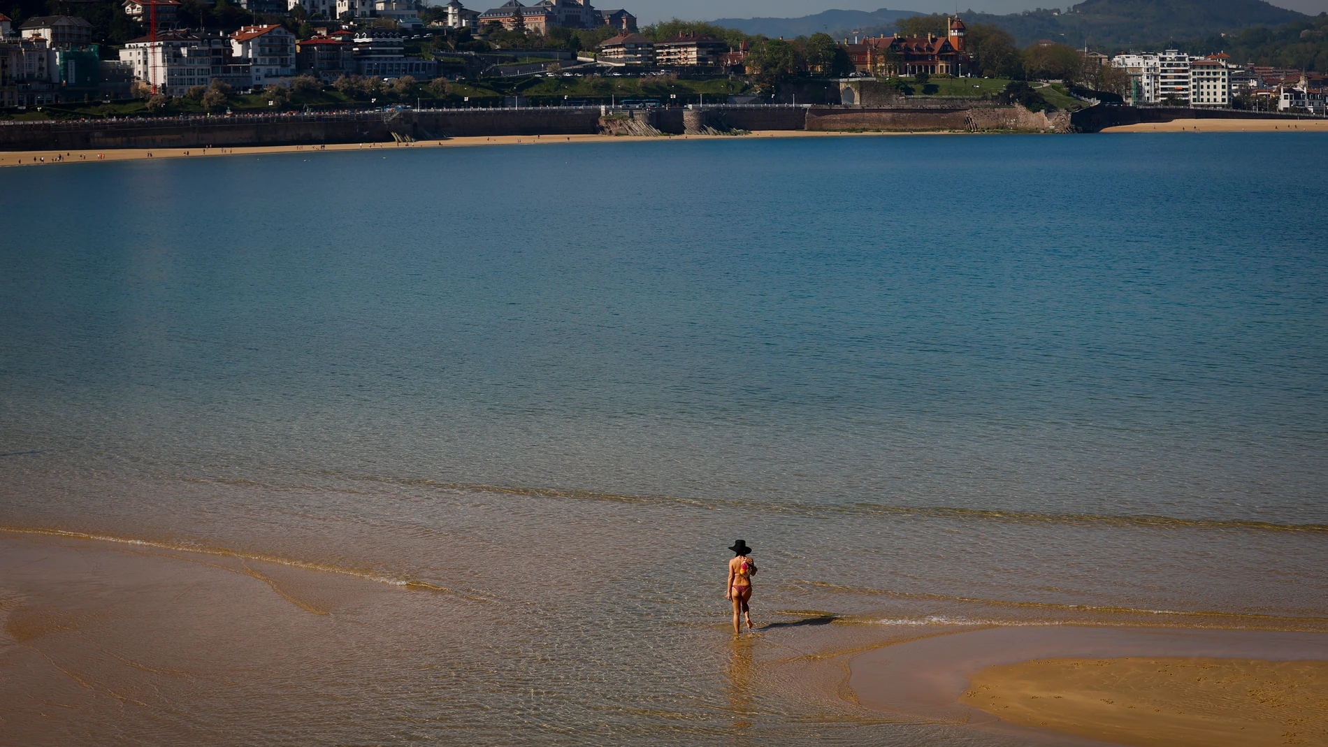Una mujer pasea por la orilla de la playa de La Concha de San Sebastián.