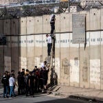 Jóvenes palestinos tratan de trepar por uno de los muros de acceso a Jerusalén