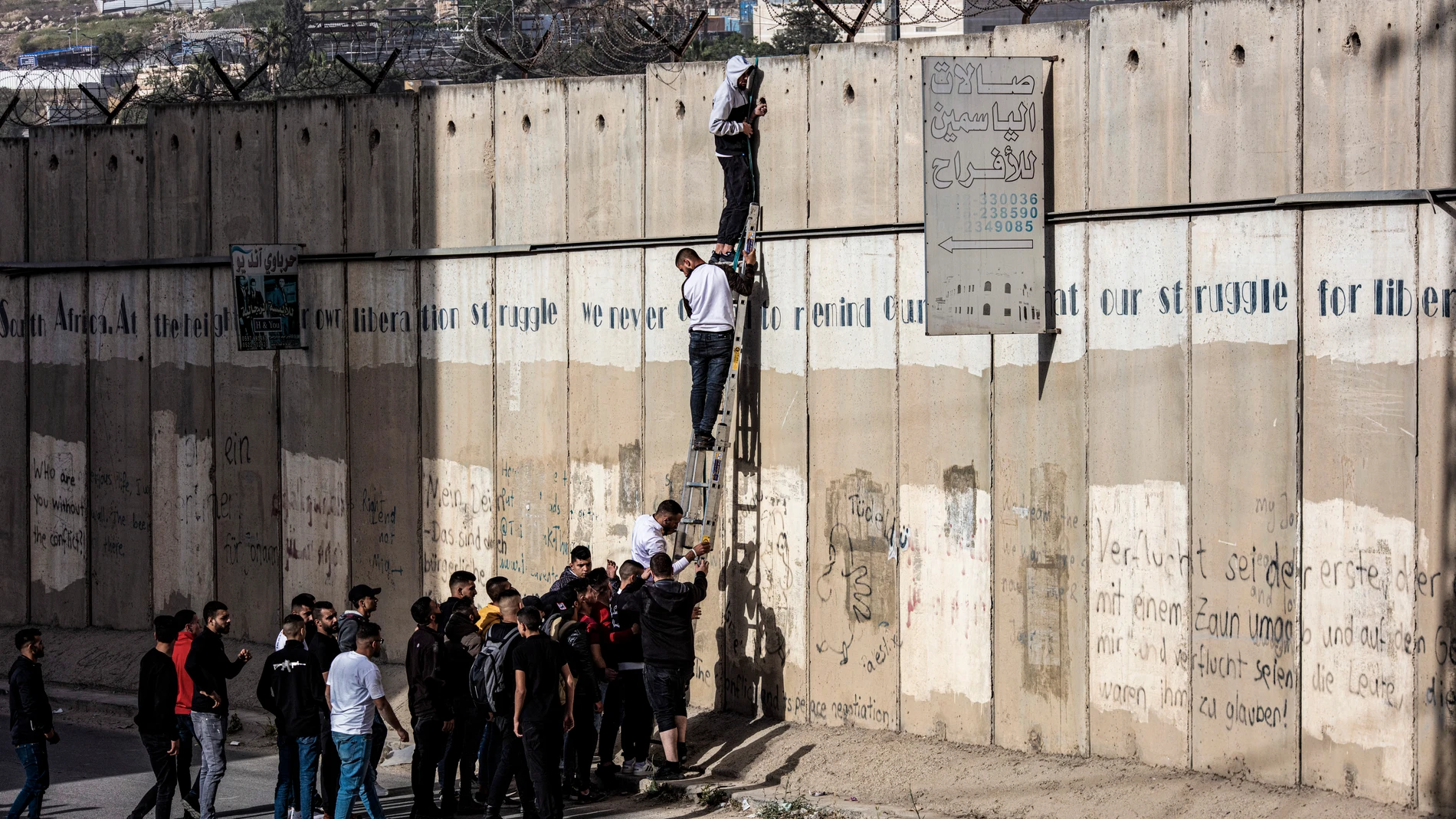 Jóvenes palestinos tratan de trepar por uno de los muros de acceso a Jerusalén