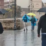 Dos personas con paraguas y chubasqueros caminan bajo la lluvia, a 3 de mayo de 2022, en Valencia