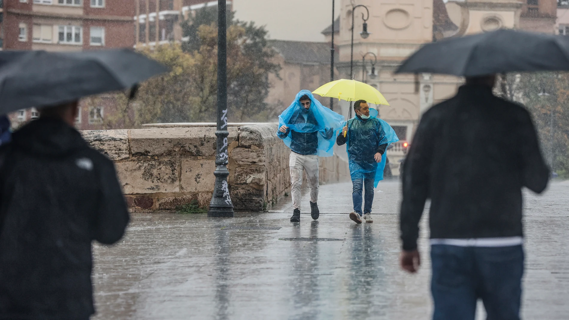 Dos personas con paraguas y chubasqueros caminan bajo la lluvia, a 3 de mayo de 2022, en Valencia