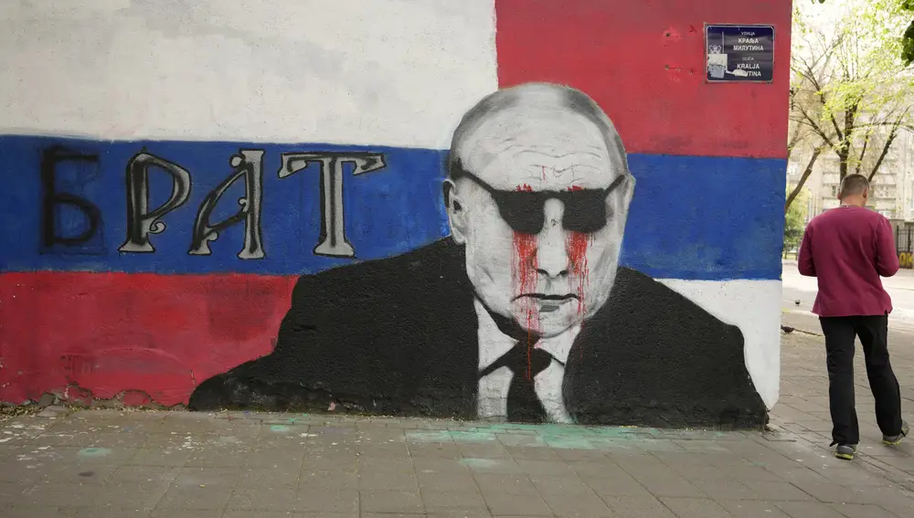 A man passes by a mural depicting the Russian President Vladimir Putin that reads: ''Brother'' vandalized with paint, in Belgrade, Serbia, Saturday, May 7, 2022. Despite having to pay a big price Serbia for not introducing sanctions to Russia, Serbia will not do it , Serbian President Vucic said, but despite that the country will stay on its path toward the EU. (AP Photo/Darko Vojinovic)