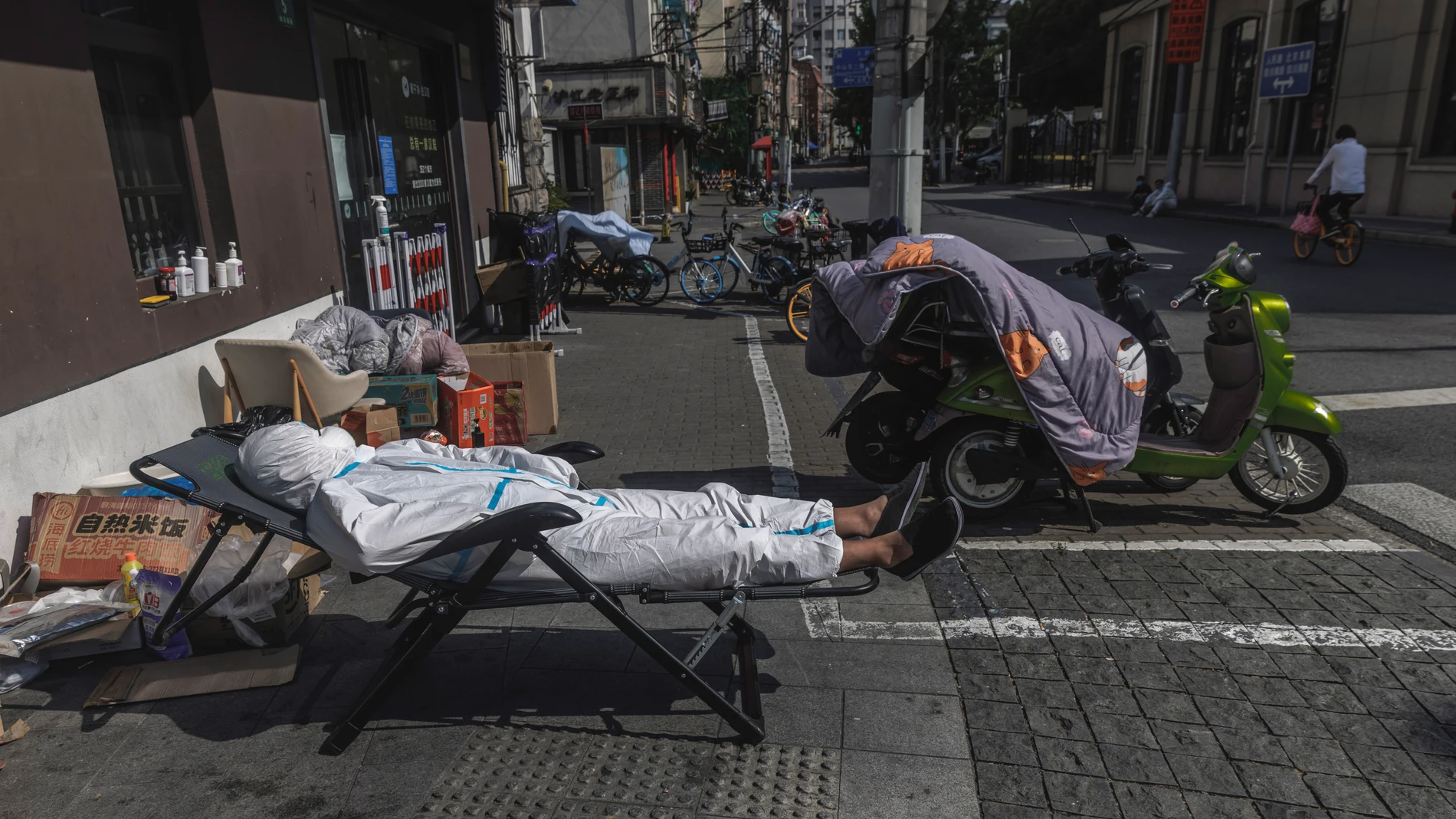 Un repartidor de comida a domicilio descansa en plena calle en Shanghai