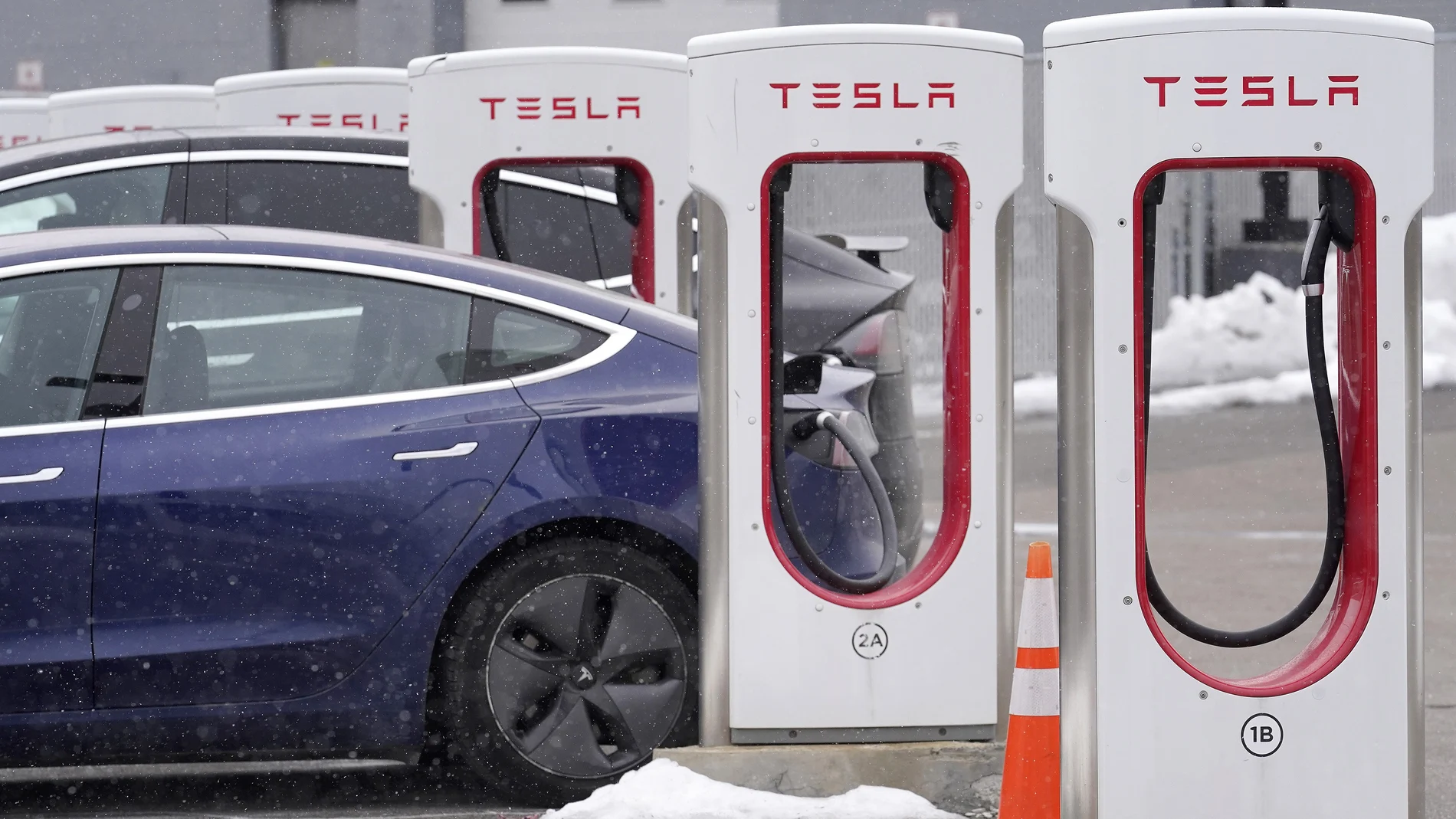 FILE - A Tesla electric vehicle, left, sits in a charging station at a dealership, Thursday, Feb. 18, 2021, in Dedham, Mass. Shares of Tesla and Twitter have tumbled this week as investors deal with the fallout and potential legal issues surrounding Tesla CEO Elon Musk and his $44 billion bid to buy the social media platform. Of the two, Musk's electric vehicle company has fared worse, with its stock down almost 16% so far this week to $728. (AP Photo/Steven Senne, File)