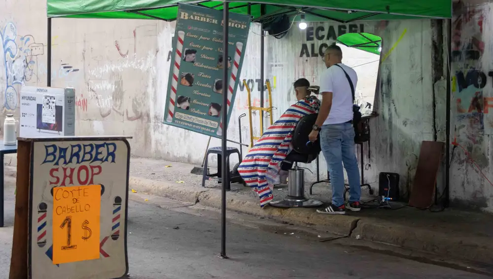 Un barbero atiende a un cliente en una barbería callejera, el 12 de mayo de 2022, en Caracas (Venezuela)