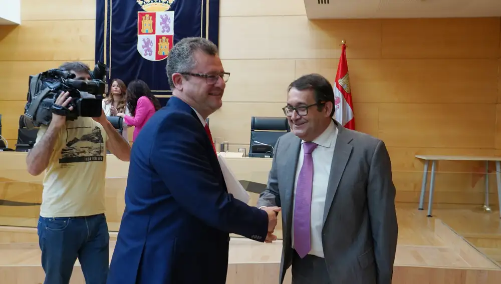 El consejero de Agricultura, Ganadería y Desarrollo Rural, Gerardo Dueñas, saluda al socialista Juan Luis Cepa, antes de comparecer en las Cortes para dar cuenta de su programa de Gobierno