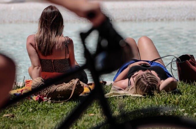 Dos mujeres toman el sol en el jardín del rio Turia de Valencia.