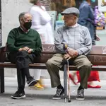Dos señores mayores en un banco sentados en el que se puede ver a uno de ellos con mascarilla y el otro sin ella