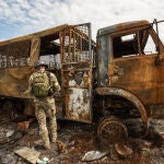 Un soldado ucraniano patrulla hoy, frente a un vehículo destruido durante una batalla en la entrada de la ciudad de Járkov (Ucrania)