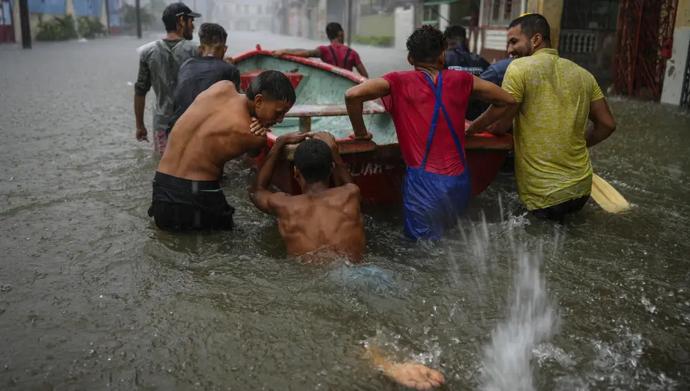 Voluntarios intentan sacar un coche, que quedó atascado por las fuertes lluvias