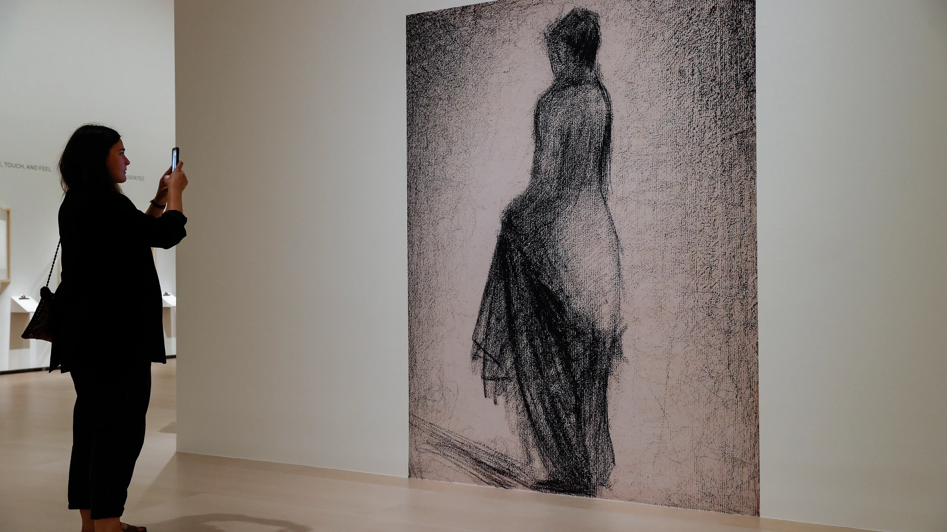 Una visitante fotografía un dibujo ampliado de Seurat en el Museo Guggenheim de Bilbao
