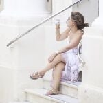 Una señora bebe agua mientras descansa sentada en una escalera en Sevilla