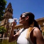 Una joven bebe agua para refrescarse en el Patio de los Naranjos de Córdoba