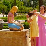 Una madre refresca a su hija en una fuente de el Parque de María Luisa