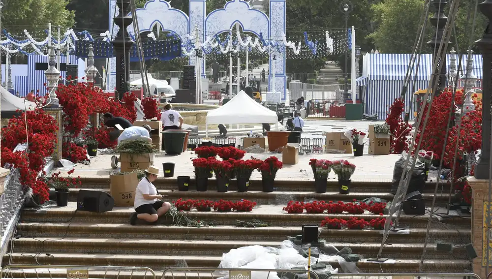 Trabajadores decorando con flores el puente de la Plaza de España con la portada de fondo