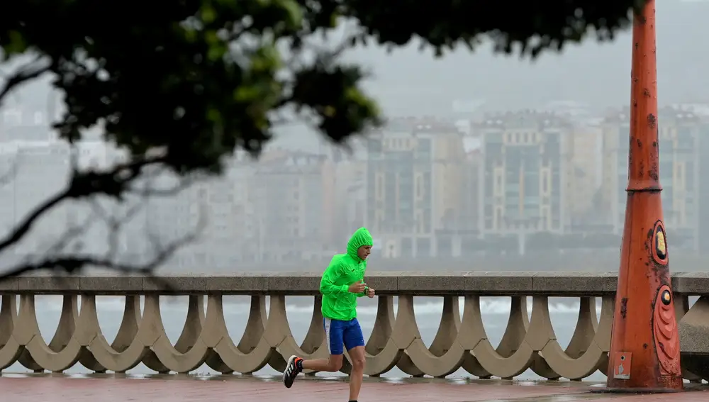 Un hombre, con chubasquero, corre por el Paseo Marítimo de La Coruña, a 19 de junio de 2022, en A Coruña, Galicia, (España).