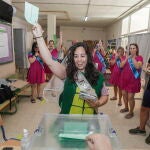 Una joven con velo y disfrazada para celebrar su despedida de soltera se dispone a introducir su papeleta de voto en una urna del IES La Caleta en el barrio de La Viña en Cádiz