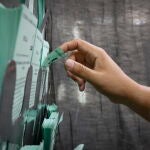 Una persona elige una papeleta en un colegio electoral