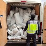 Un agente ante una furgoneta cargada con sacos de marihuana