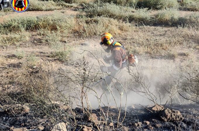 Un agente de la brigada forestal actuando sobre el terreno incendiado en Riba-roja