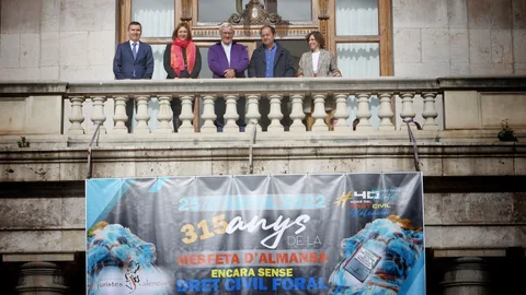 Miembros de la Associació de Juristes Valencians en el balcón del Ayuntamiento de Valencia junto a una pancarta reivindicativa