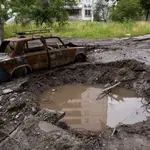 Un automóvil destruido junto al cráter dejado por una explosión en la entrada del barrio Saltivka de Jarkiv