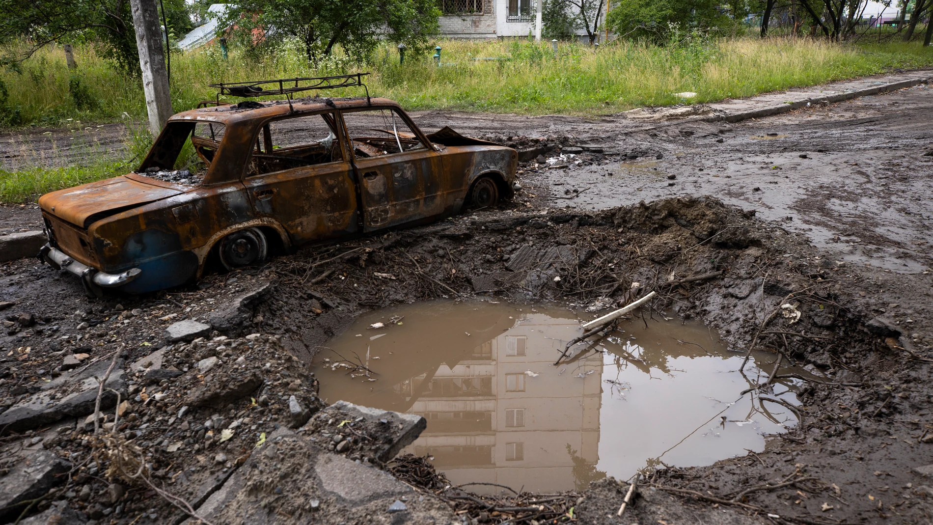 Un automóvil destruido junto al cráter dejado por una explosión en la entrada del barrio Saltivka de Jarkiv