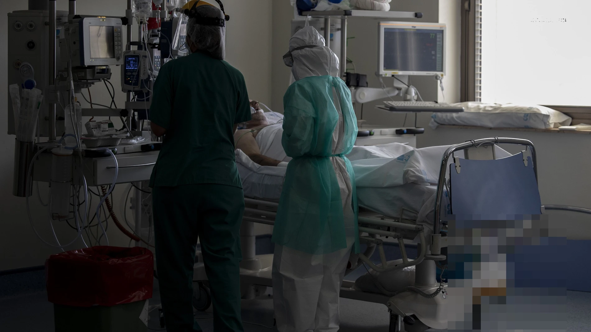 Dos sanitarios atienden a un paciente en la Unidad de Cuidados Intensivos (UCI) dedicada a enfermos de coronavirus del Hospital Universitario Ramón y Cajal, en Madrid.