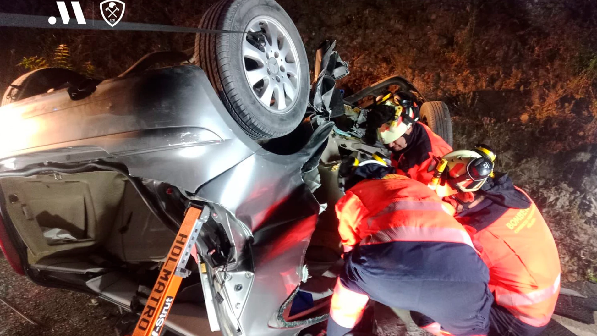 Efectivos del Consorcio Provincial de Bomberos durante la intervención ayer de madrugada en un accidente de tráfico que se ha producido en la carretera A-374, en el que han perdido la vida tres jóvenes, al menos dos de ellos menores, tras huir de un control policial en el término municipal de Ronda (Málaga)