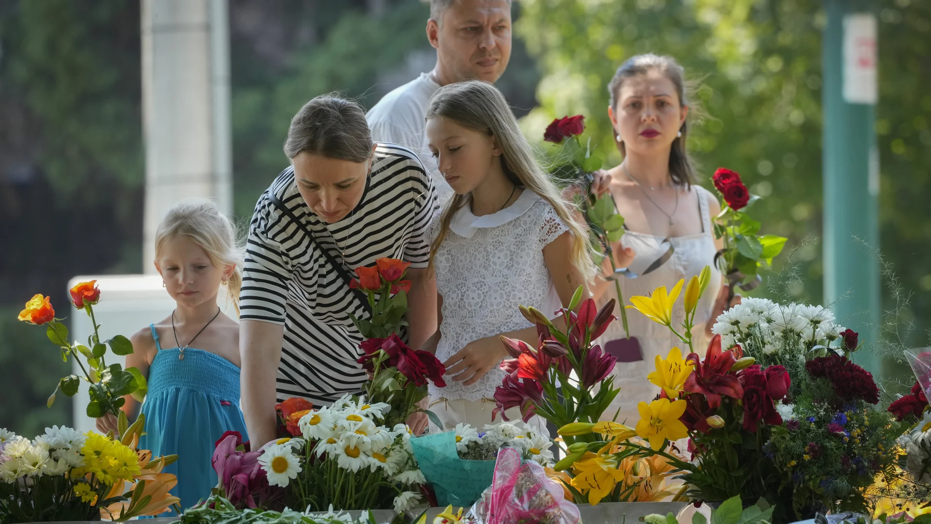 Familias dejan flores en homenaje a las víctimas del bombardeo contra el centro comercial de Kremenchuk, en Ucrania