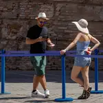 Unos turistas se protegen del sol con sombreros junto al muro de los Reales Alcázares de Sevilla