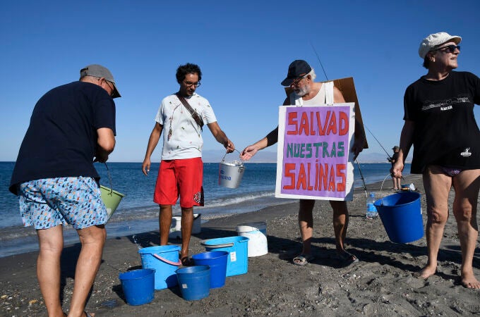 Varios voluntarios llevan este sábado agua de mar a Las Salinas del Cabo de Gata en la playa de La Fabriquilla (Almería). EFE/ Carlos Barba