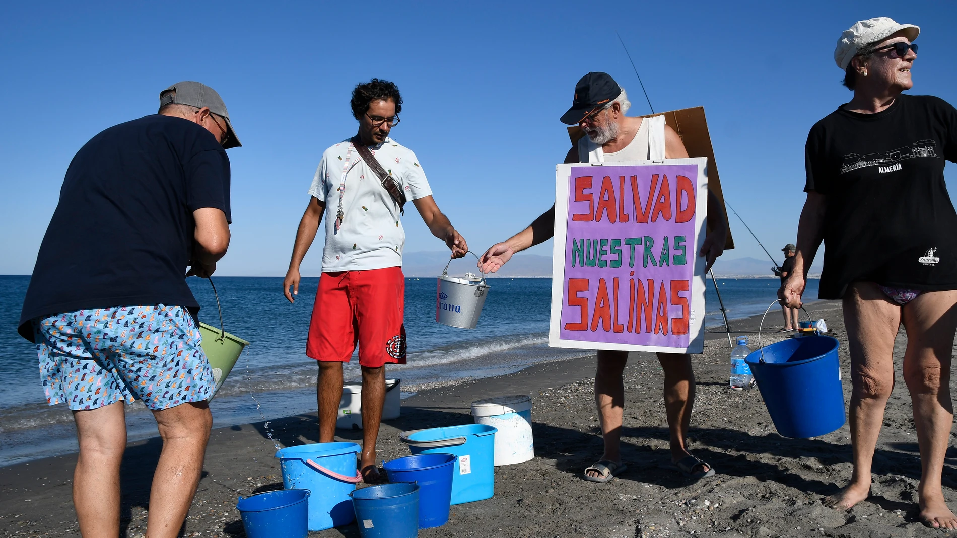Varios voluntarios llevan este sábado agua de mar a Las Salinas del Cabo de Gata en la playa de La Fabriquilla (Almería). EFE/ Carlos Barba