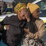 Una mujer llora junto a la escena del tiroteo de Soweto, Sudáfrica, donde 15 personas han sido asesinadas.