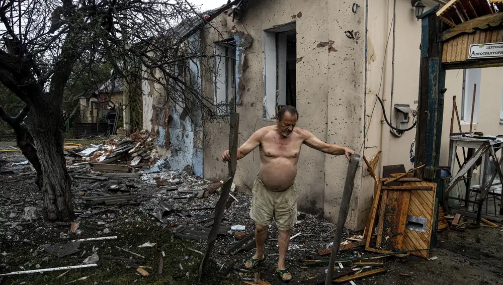 Un lugareño limpia los escombros de su casa que fue destruida después de un ataque ruso en un barrio residencial en el centro de Jarkov