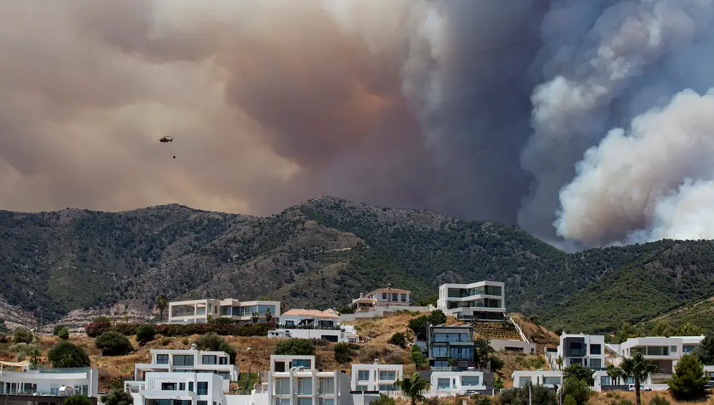 Un helicóptero trabaja durante las tareas de extinción del incendio declarado en el paraje El Higuerón de Mijas (Málaga),