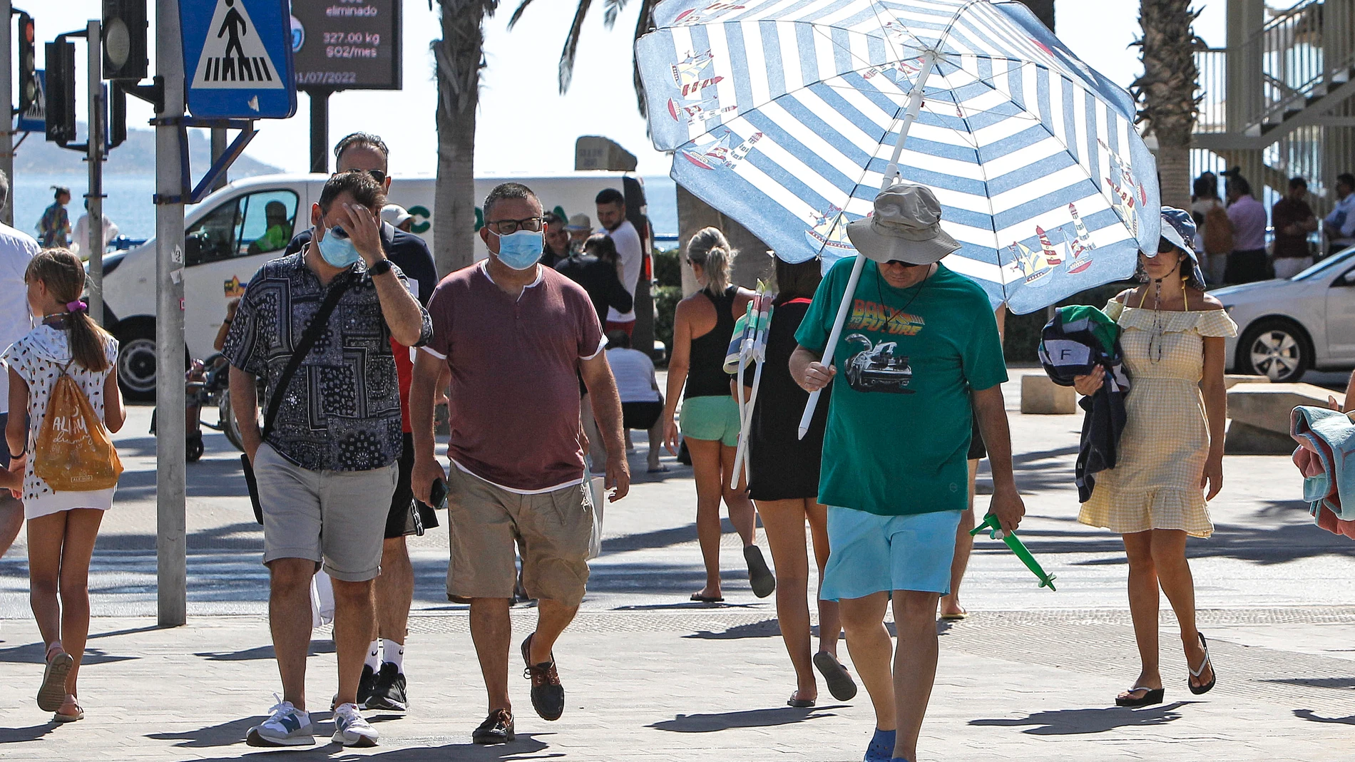 Un hombre se protege del intenso calor con una sombrilla de playa por las calles de la ciudad de Alicante.