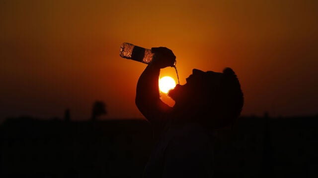 Un hombre bebe agua en el puente romano de Córdoba. EFE/Salas