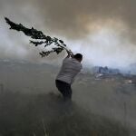 Un voluntario utiliza una rama de árbol tratando de evitar que un incendio forestal llegue a las casas en Casal da Quinta, a las afueras de Leiria, en el centro de Portugal