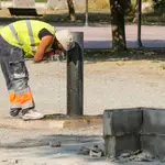 Un trabajador se refresca en un fuente de un parque de Lleida
