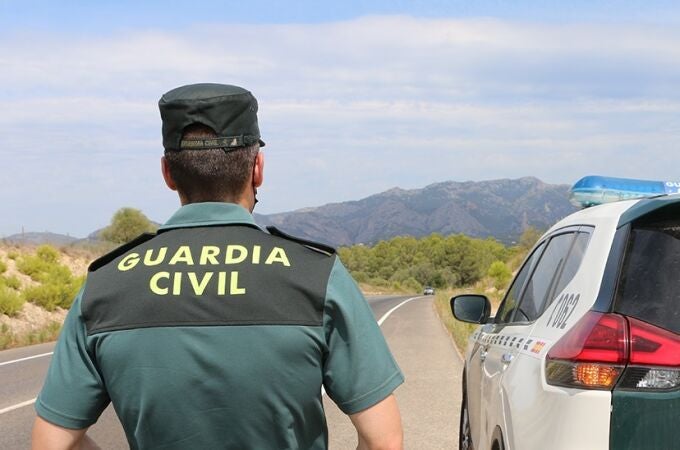 Un agente de la Guardia Civil junto a un vehículo en una carretera. GUARDIA CIVIL (Foto de archivo)