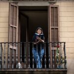 Una joven lee un libro en el balcón de su casa