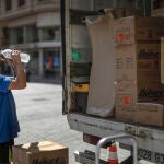 Un trabajador de una empresa de mudanzas bebe agua para combatir el calor en una calle del centro de Valencia
