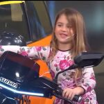 La niña, feliz, no se imagina que la moto está encendida