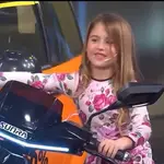 La niña, feliz, no se imagina que la moto está encendida
