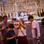 Turistas haciéndose selfies con su teléfono móvil en la plaza de la Cibeles