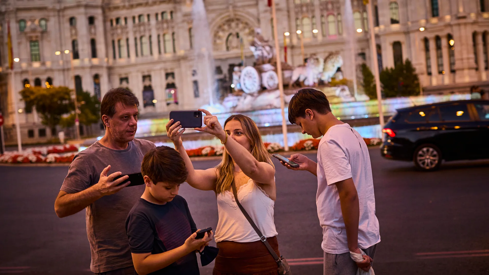 Turistas haciéndose selfies con su teléfono móvil en la plaza de la Cibeles