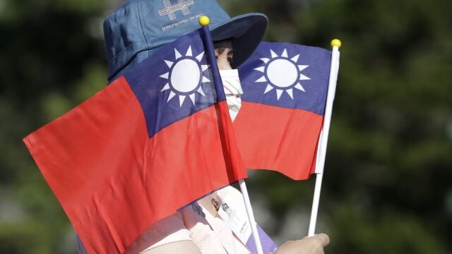 Una mujer sostiene varias banderas de Taiwán durante la fiesta nacional