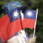 Una mujer sostiene varias banderas de Taiwán durante la fiesta nacional