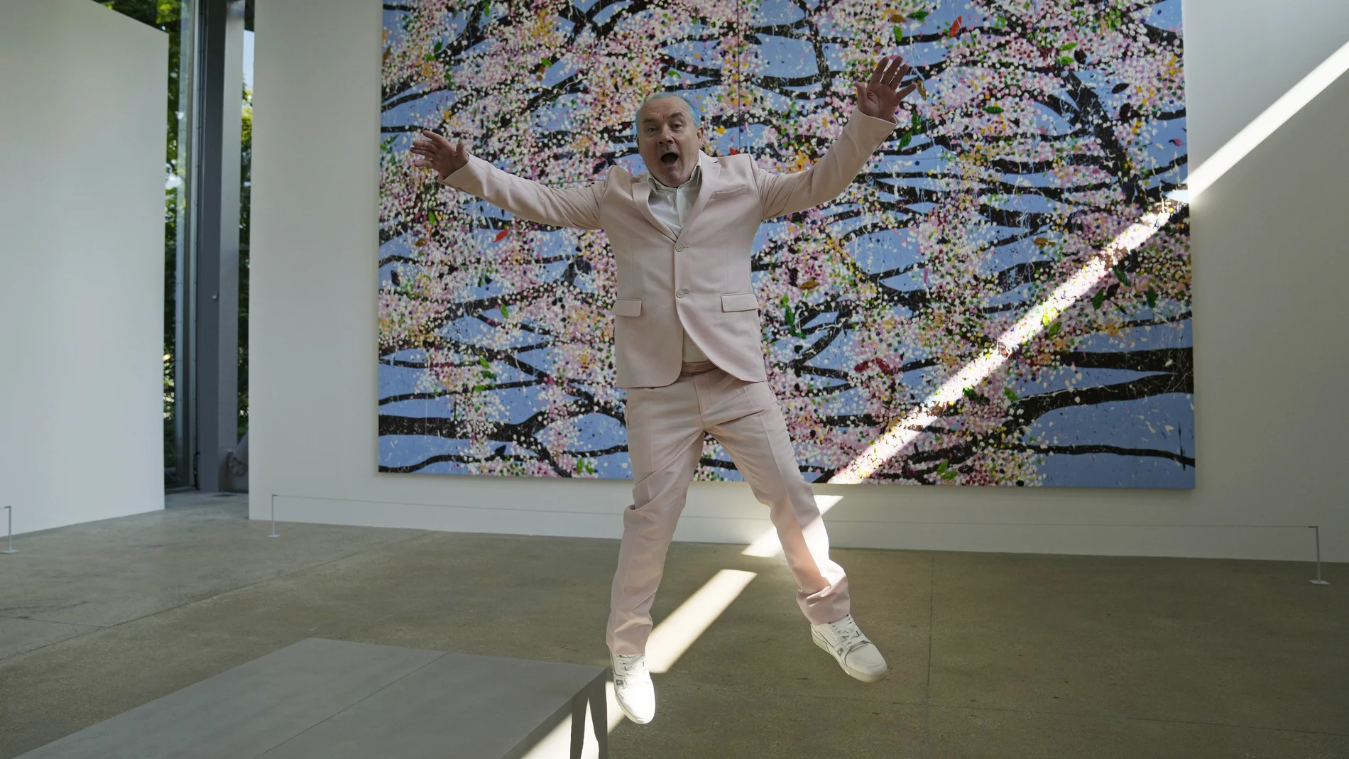 El artista Damien Hirst salta delante de una de sus pinturas